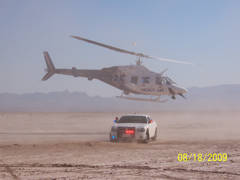 A helicopter landing next to a police cruiser in a desert area